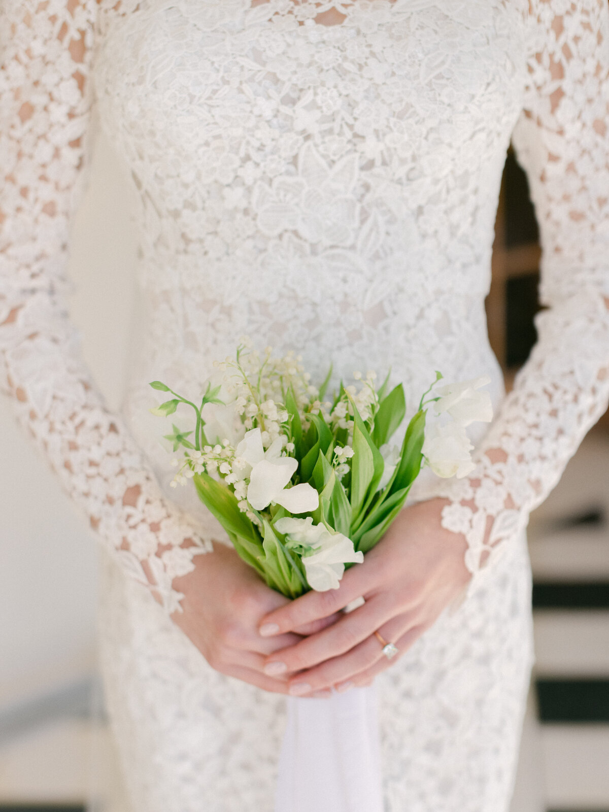 bride in white lace wedding dress holding small floral bouquet