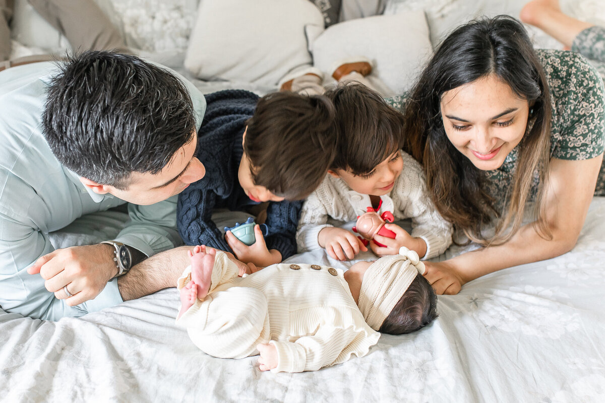 A joyful family welcomes their newborn with love – captured by a Birmingham newborn photographer. Big brothers excitedly gather around their baby sister, as mom and dad share a moment of warmth and connection during this lifestyle newborn session at home.