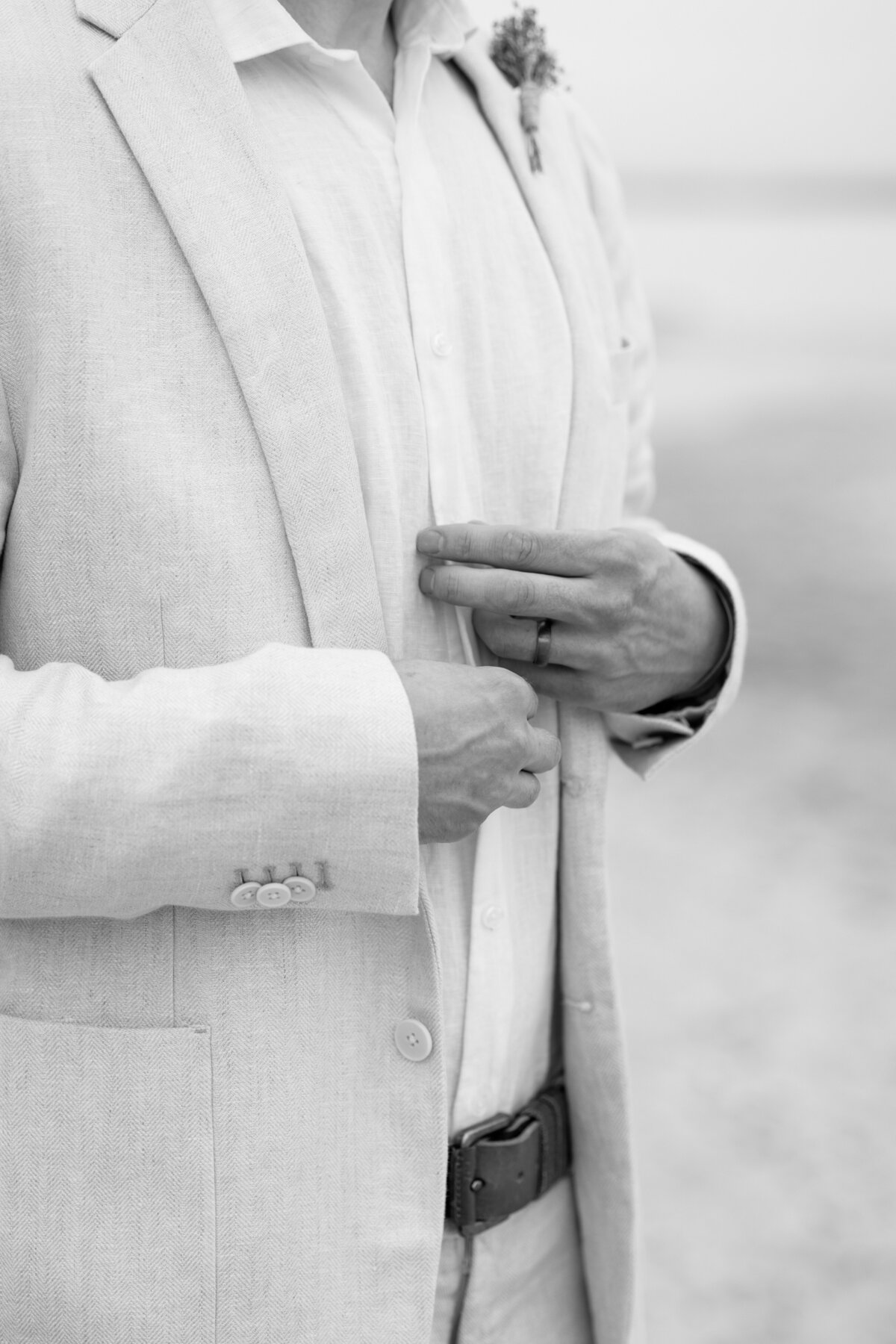 Black and white close up portrait of groom adjusting his clothing.