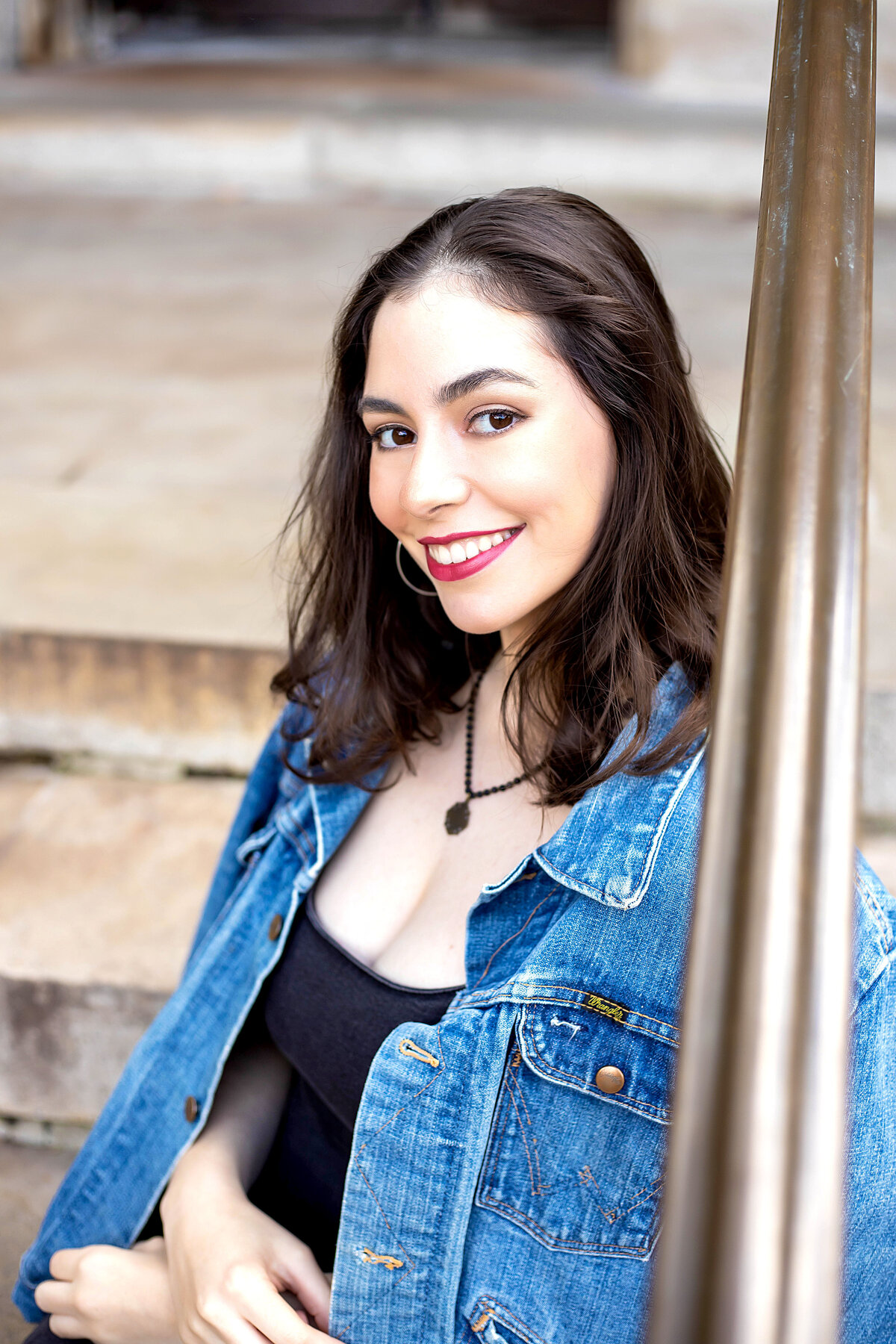 Ann Arbor U of M Law Quad Senior Photoshoot | Ann Arbor Michigan Senior Photographer, Senior girl with black hair in blue jean jack, red lipstick, and black jean dress on steps