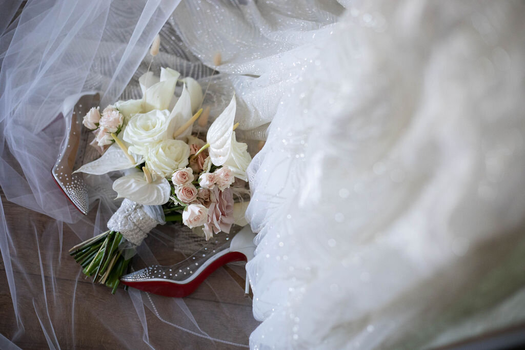 A romantic detail shot of the bride’s veil and bouquet resting atop her wedding gown, capturing the soft textures and timeless elegance.