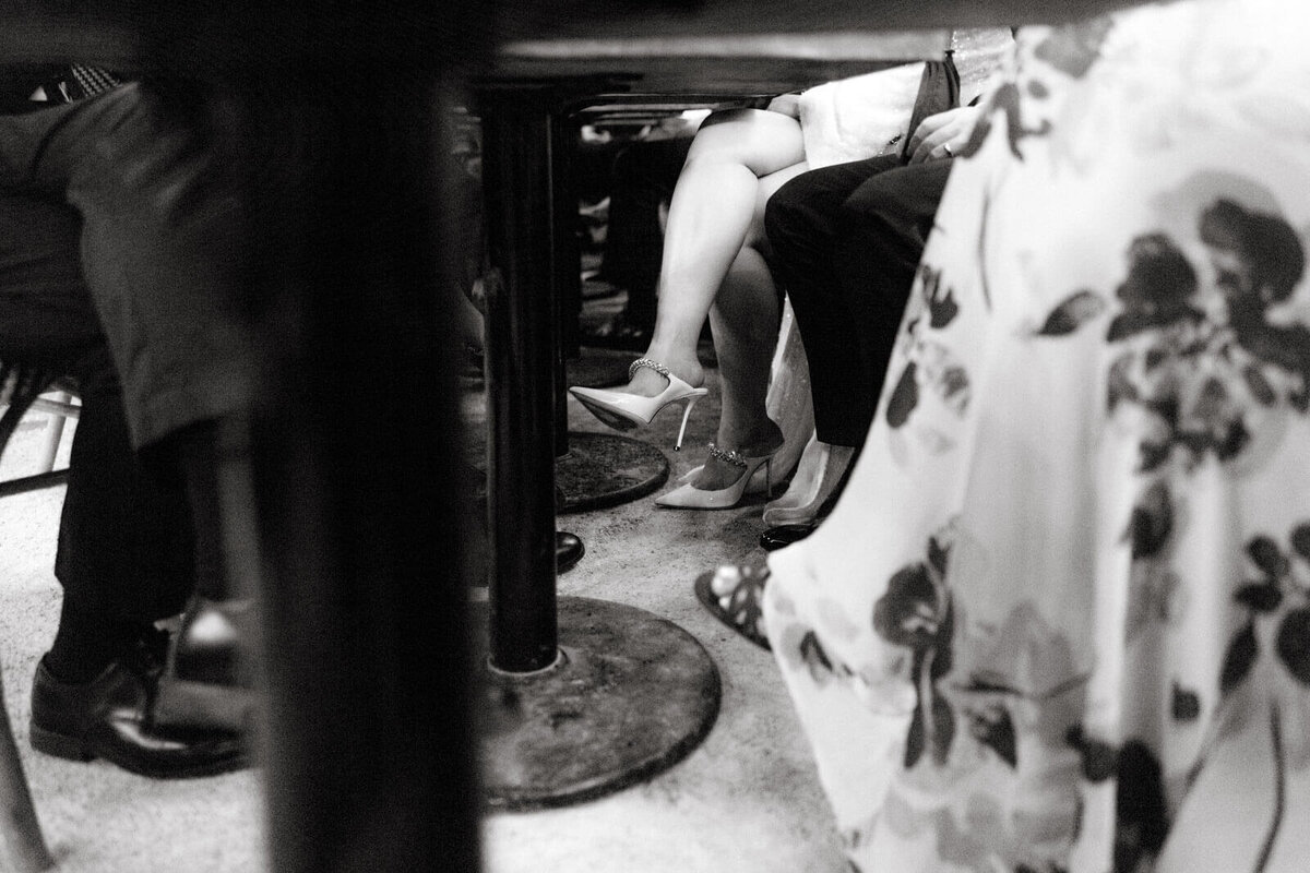 A shot from under the table, showing the bride, groom, and guests' lower body, at The High Line Hotel Chelsea, NYC. Image by Jenny Fu Studio