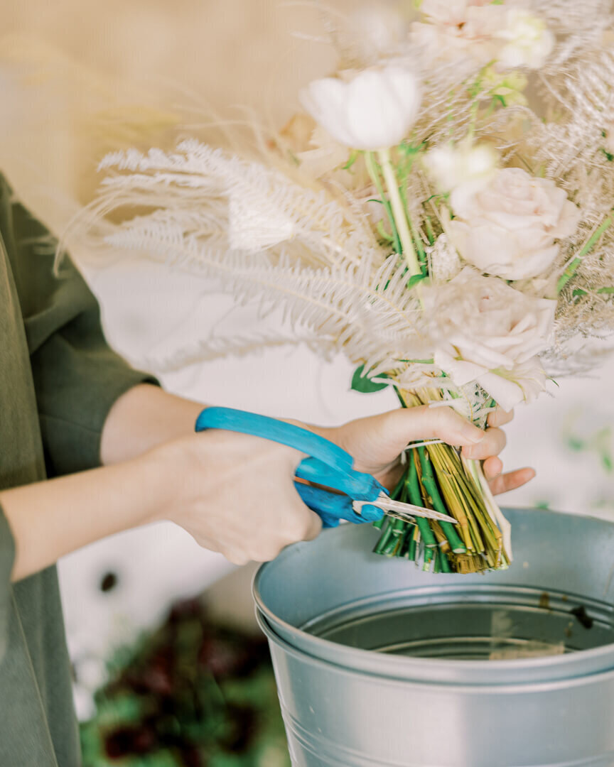 florist trim bridal bouquet in water bucket