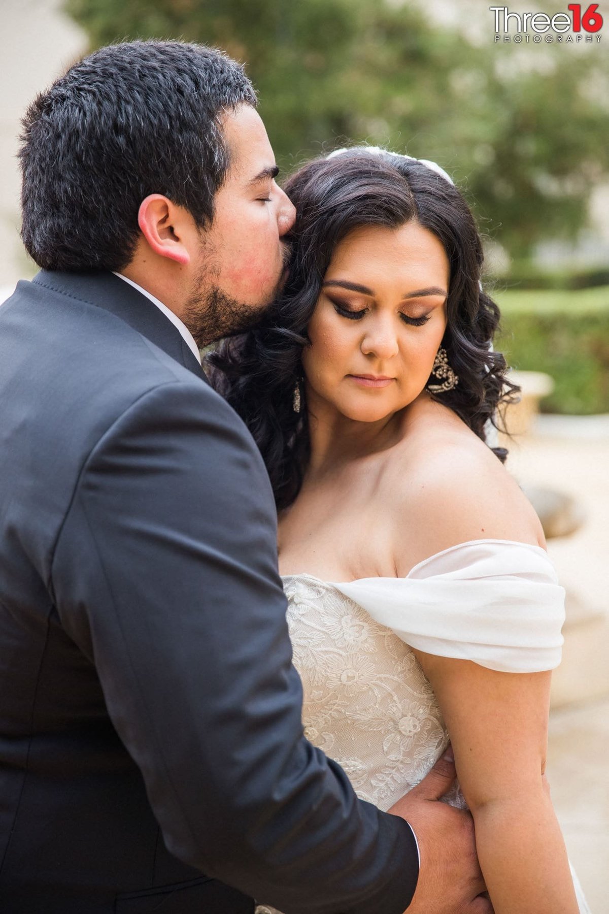 Groom to be romantically kisses his Bride's head as he embraces her