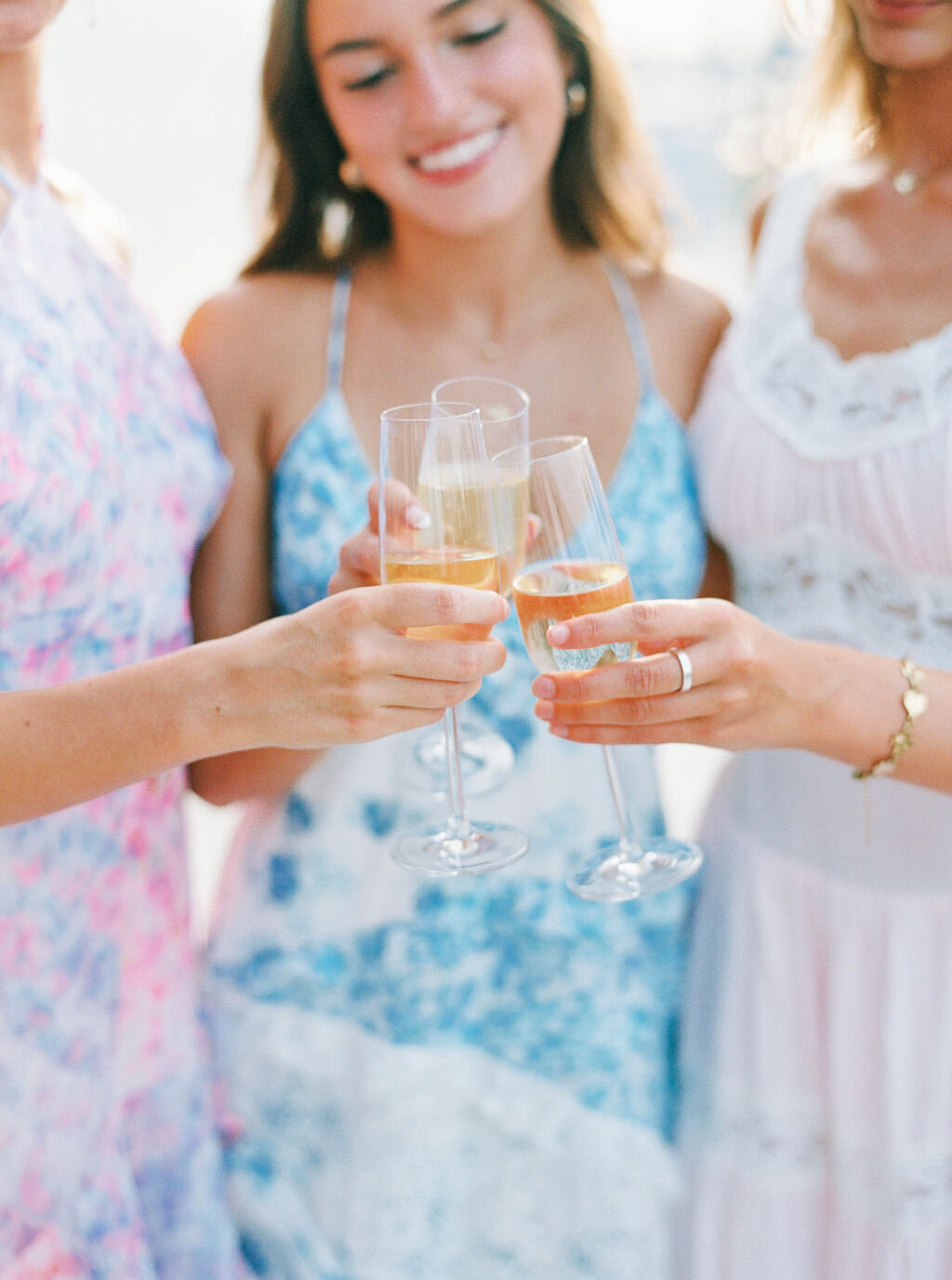 Rhode Island Wedding Photographers | Three women in pastel dresses toast with champagne glasses. 
