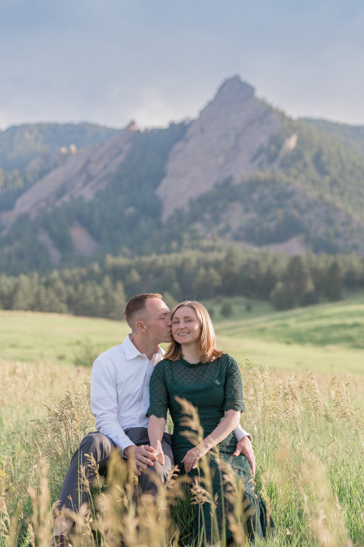 A newly engaged man kisses his fiancee on the temple during their Boulder engagement photography session