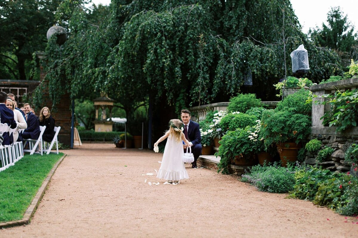 Flower girl drops petals on the way down the aisle at a luxury Chicago outdoor garden wedding.