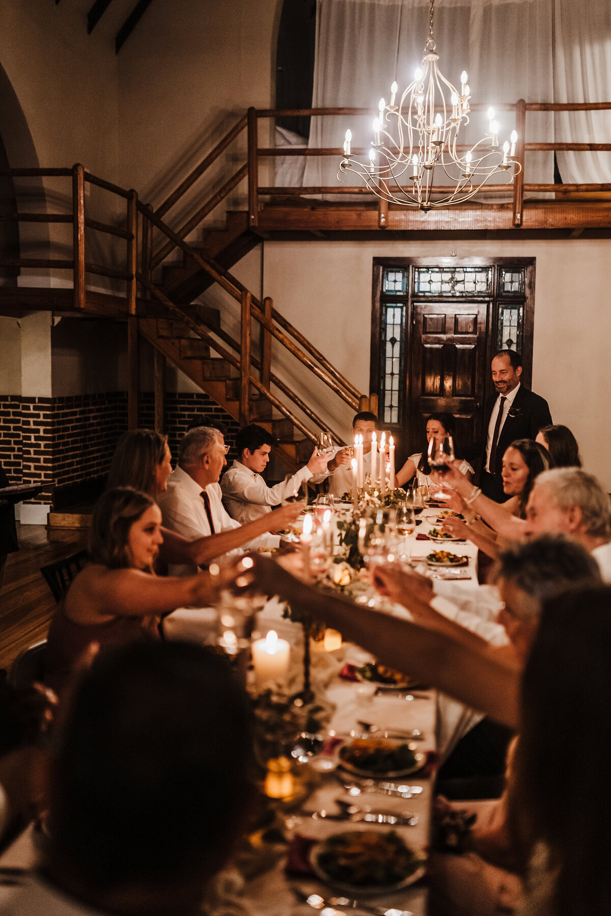 a long table of a wedding couples guests toasting to the bride and groom