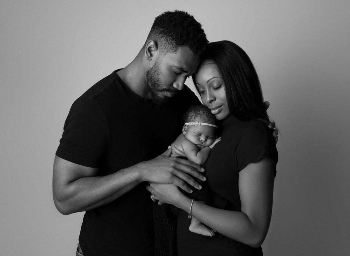 Black white couple embracing with newborn Lakeway family portrait photographer