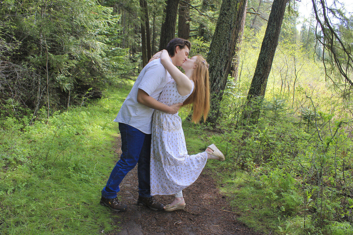 Photo of a Newley engaged couple in the green forest kissing