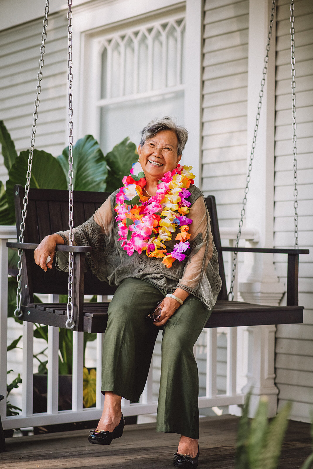 An elderly woman wearing colorful leis smiles for a Los Angeles photographer.