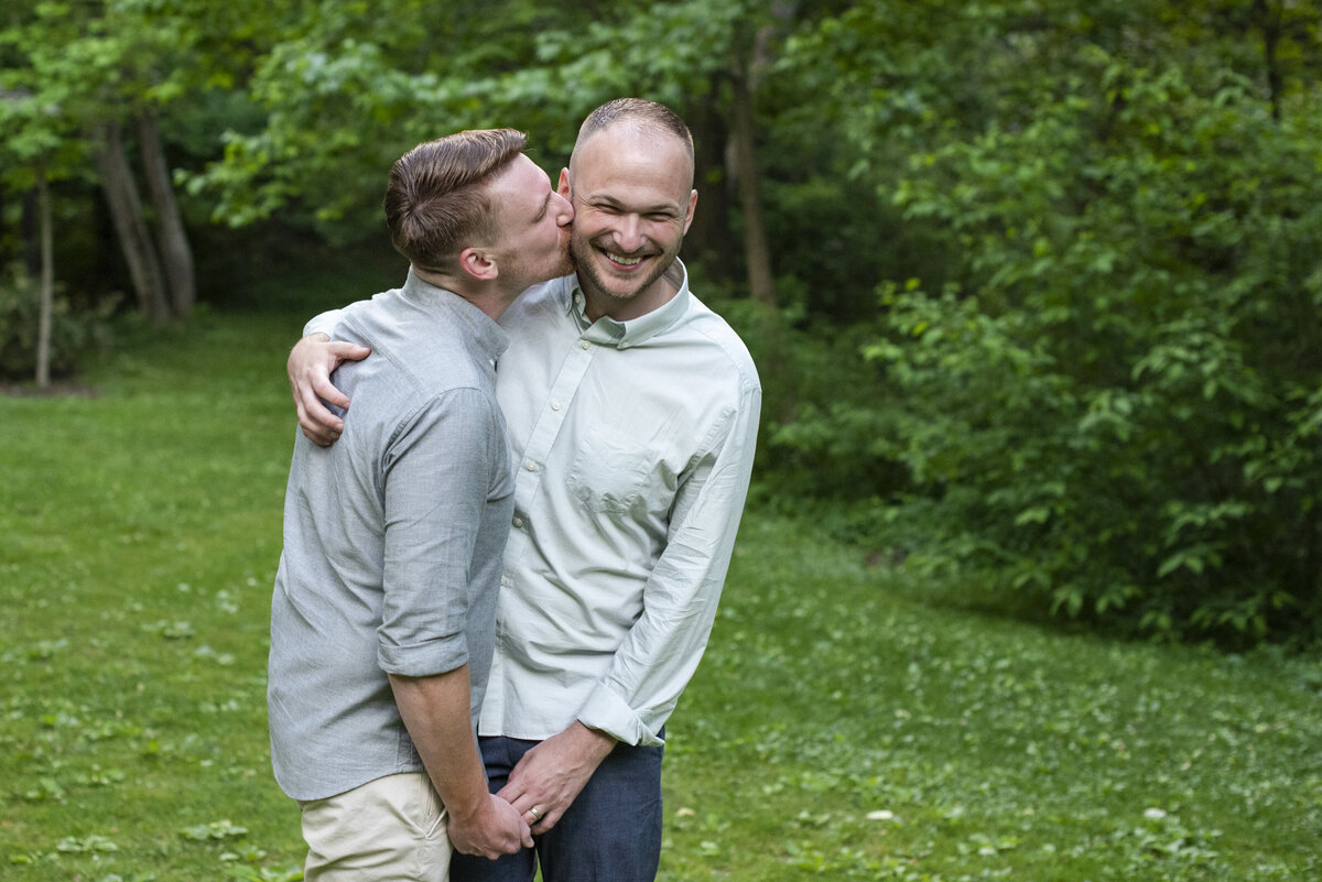 Gay couple kissing on cheek Asheville NC Botanical Gardens at Asheville