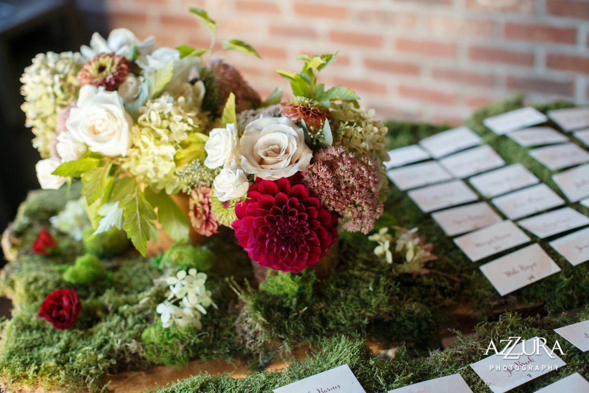 fall flower arrangement on a bed of moss as escort card table decor