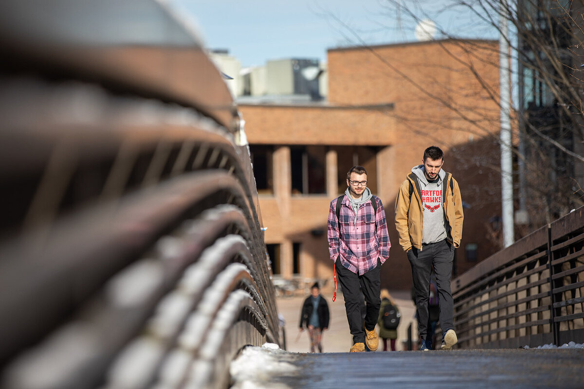 Two-male-students-walking-over-the-campus-bridge