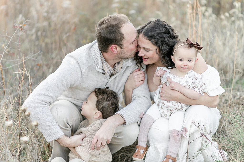 Family of 4 snuggles in a field