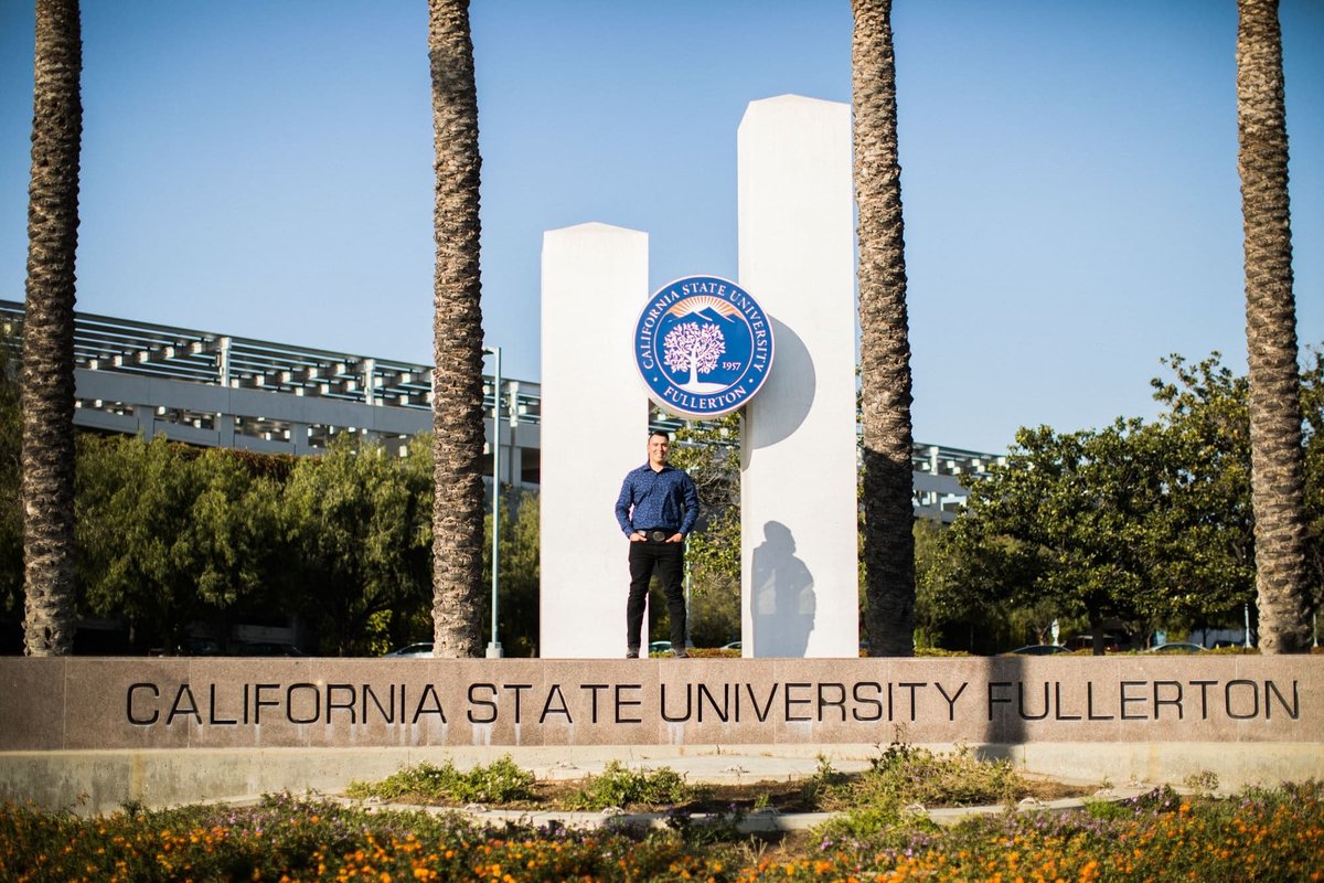 College grad student poses for senior portraits while standing on the university sign