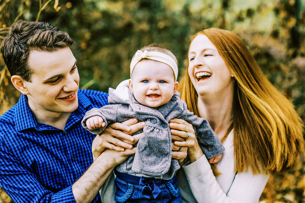 a mom and dad lift up a baby