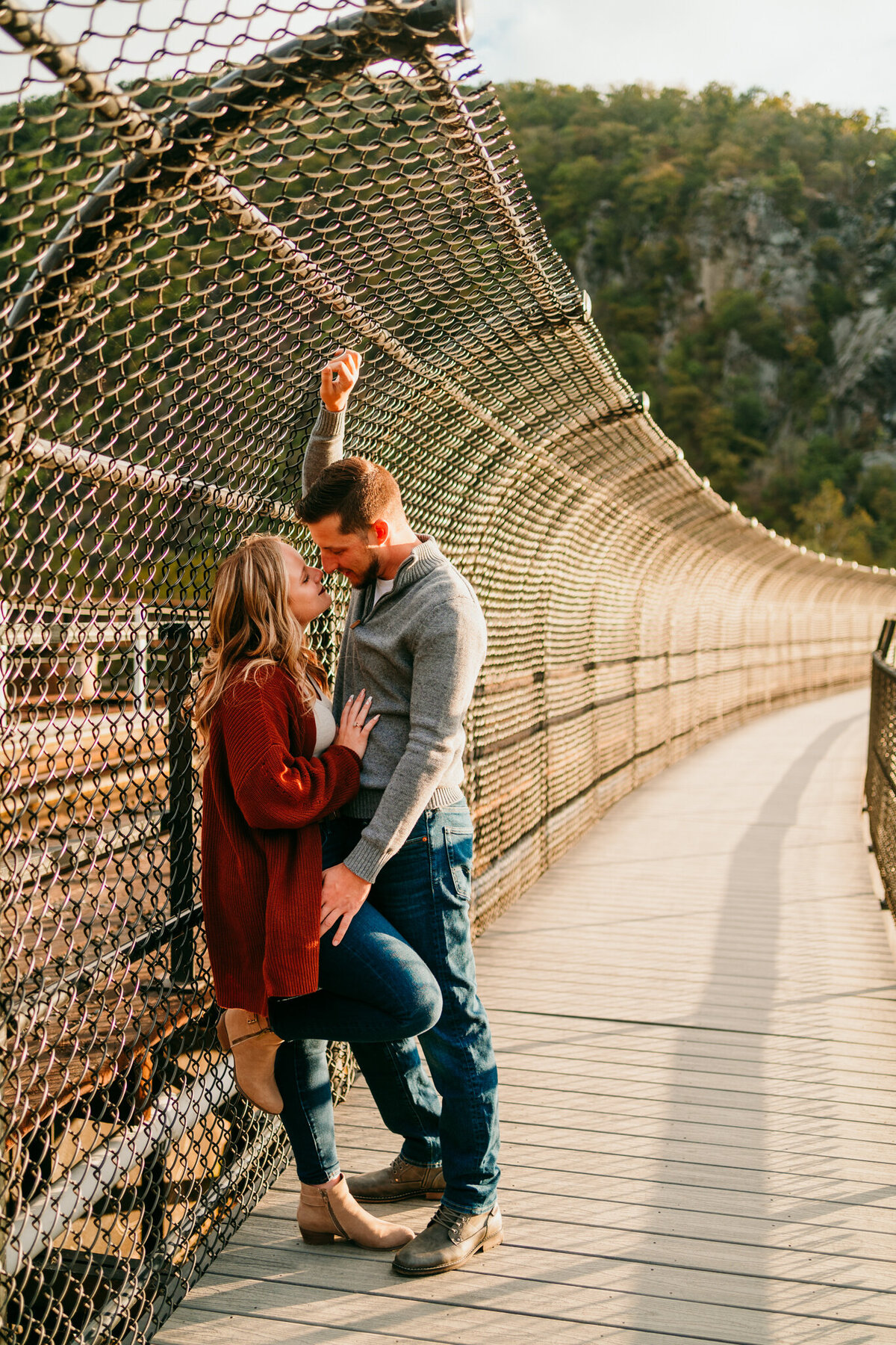 Couple kissing on a suspension bridge with scenic backdrop