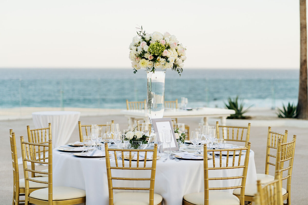 Outdoor wedding reception table with floral centerpiece by the ocean