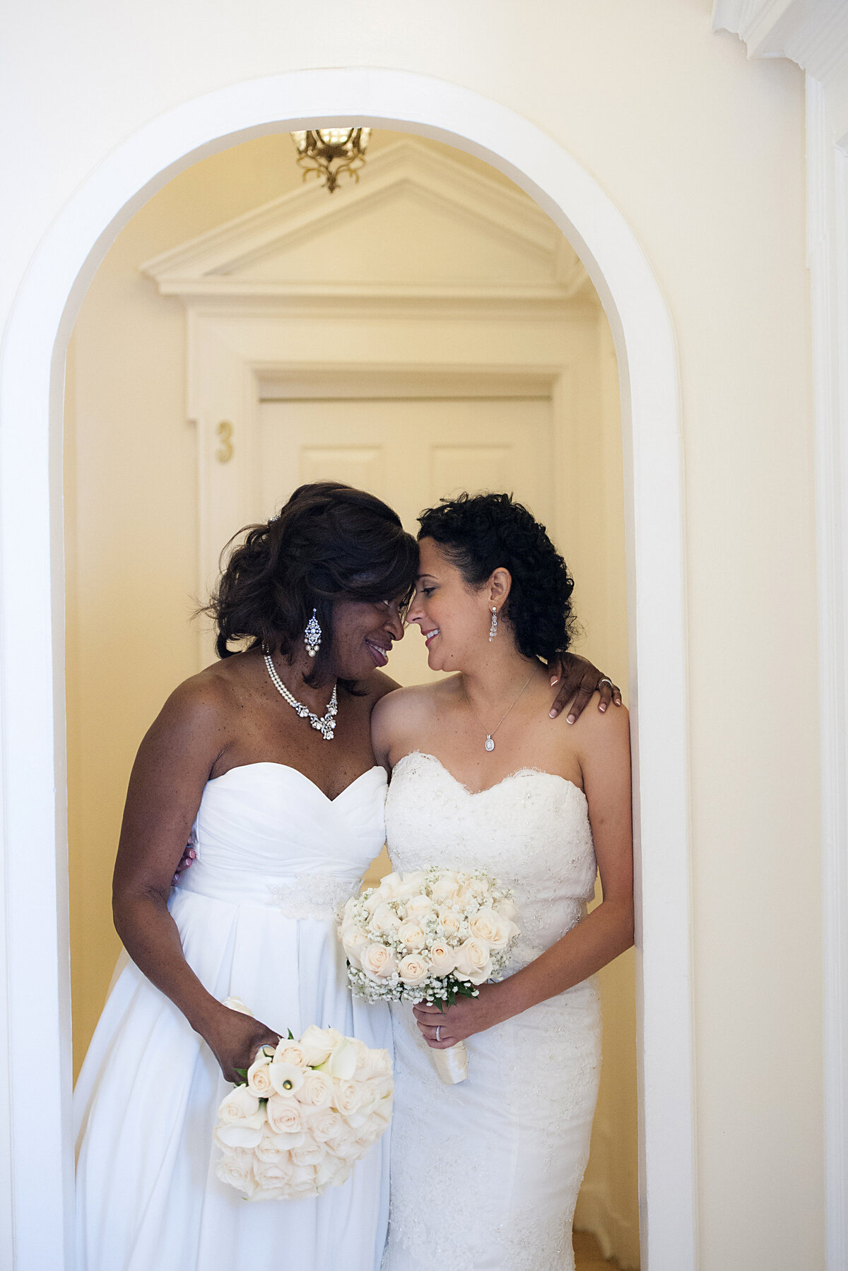 A wedding couple standing side by side with their heads together 