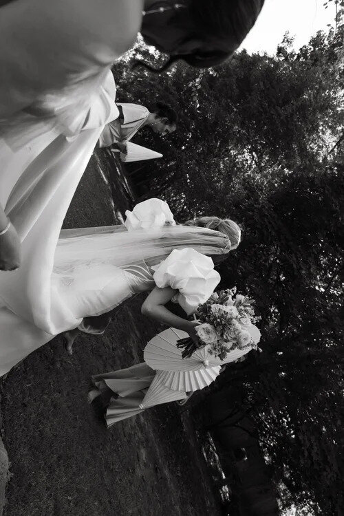 Bride in puff sleeve wedding gown walking garden path in black and white