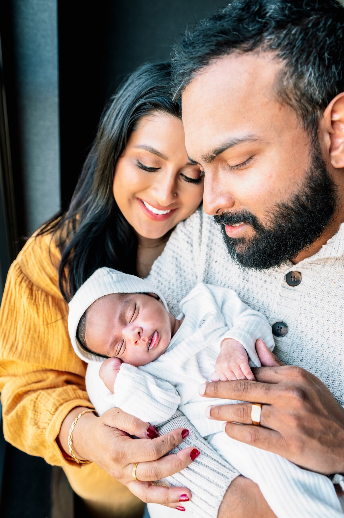 baby sleeping in mom and dads arms during a newborn photography session