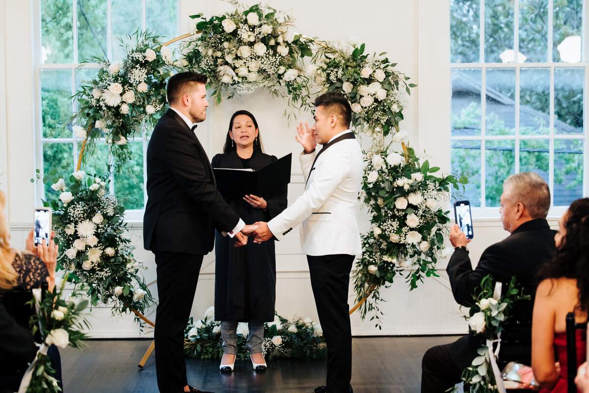 Gay wedding ceremony with white flowers and greenery.