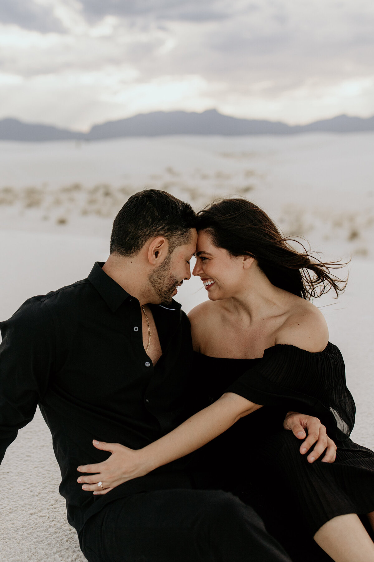 engaged couple sitting together smiling at white sands national park