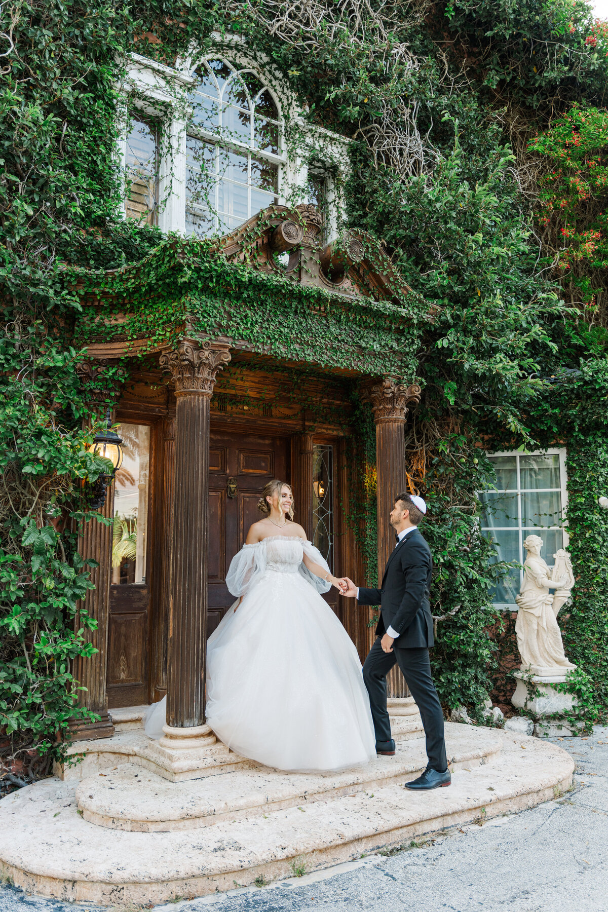 bride and grrom holding hands, she is on a step while he is down