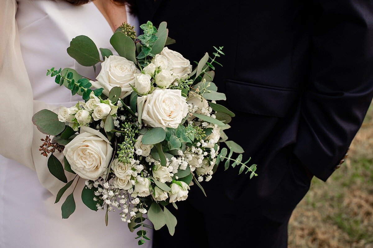 Winter white bridal bouquet of white roses, ivory tea roses, baby's breath, white veronica, silver dollar eucalyptus and blue eucalyptus.