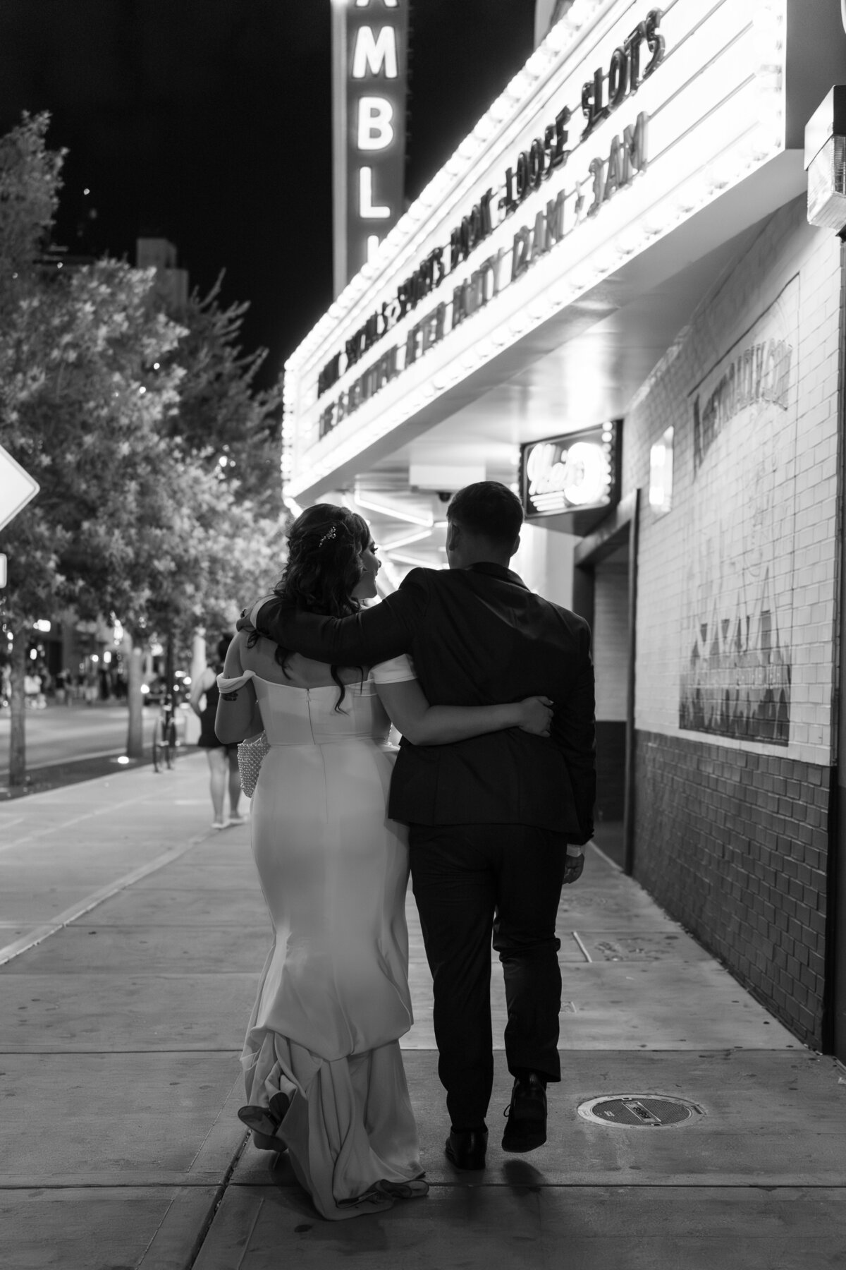 A newlywed couple walking down a city sidewalk