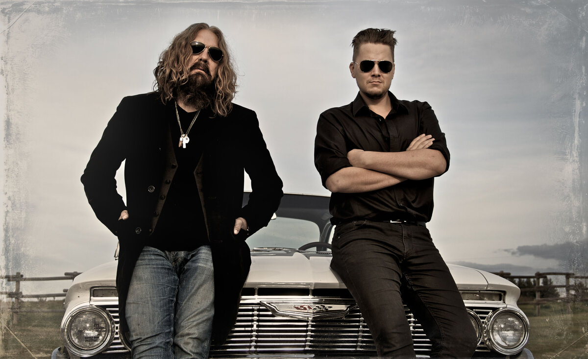 Musical duo portrait Walking The Thompsons leaning against old white car front