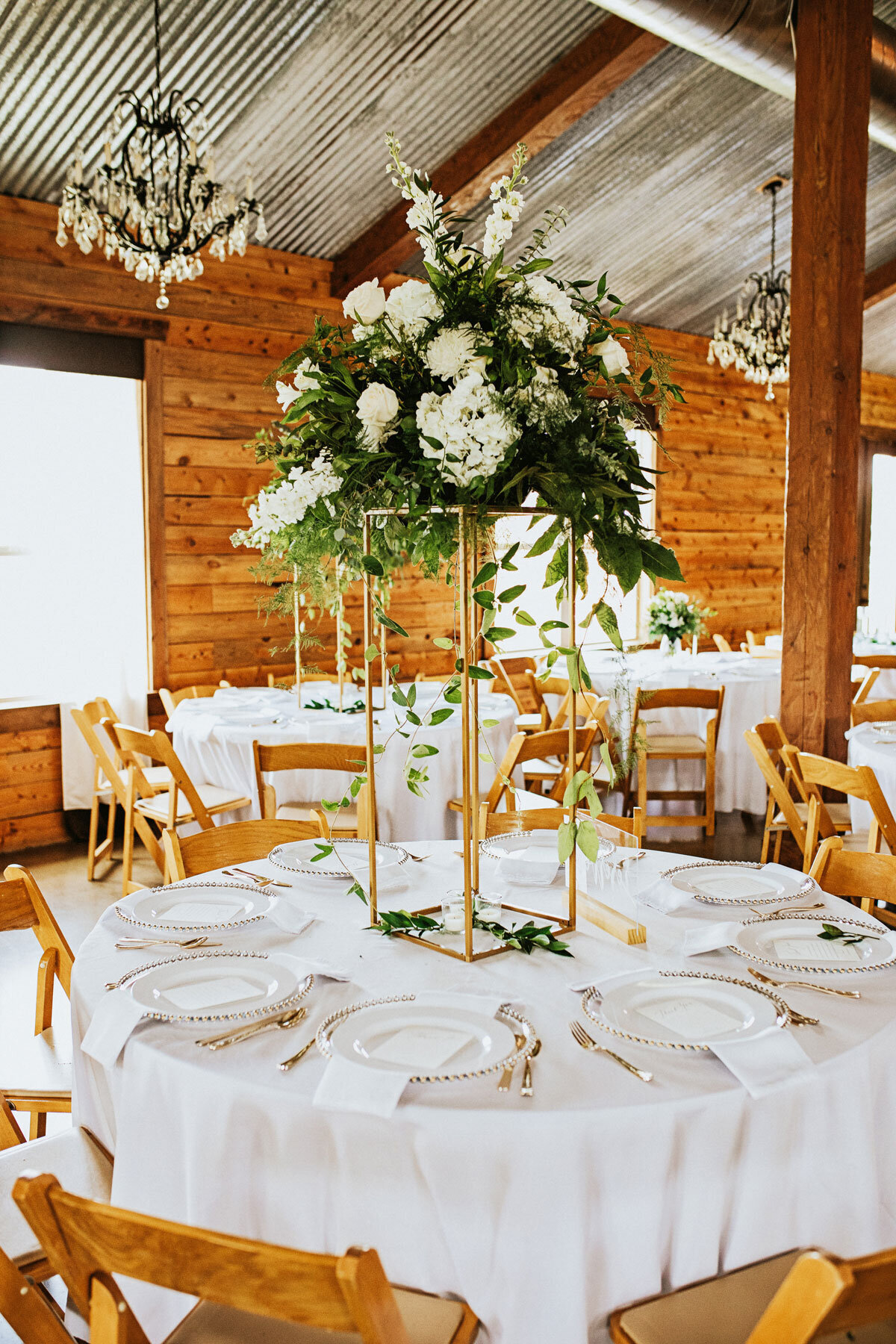 Tall gold stand with beautiful organic garden style flowers on a guest table at wedding reception