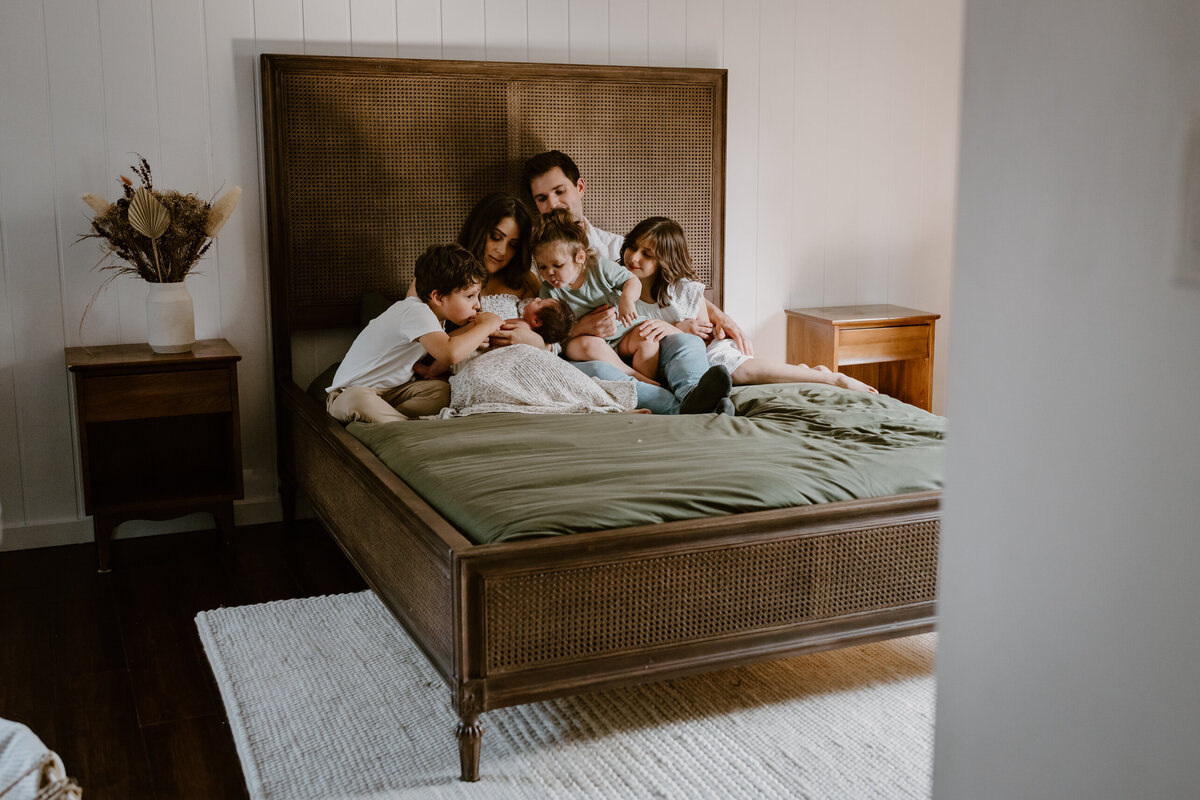 Family holding newborn in bed