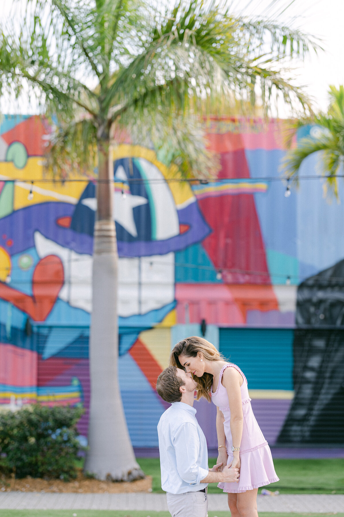 Couple sharing a sweet moment in front of a vibrant mural in Miami, captured by Rodrigo Varela Photography.