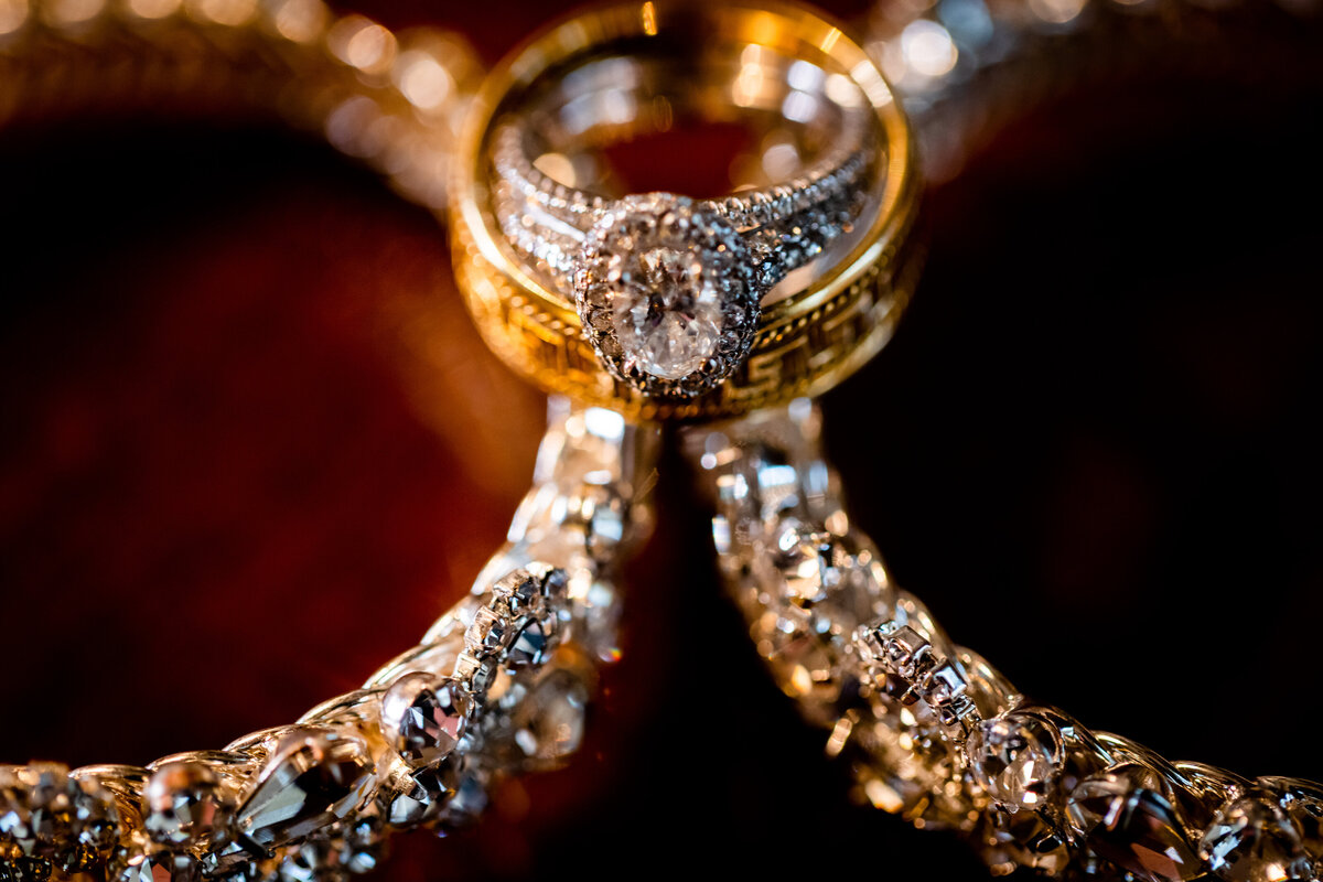 A close-up of Maria and Pete's wedding rings set against their wedding invitation, reflecting the intricate designs and symbolizing their eternal love.