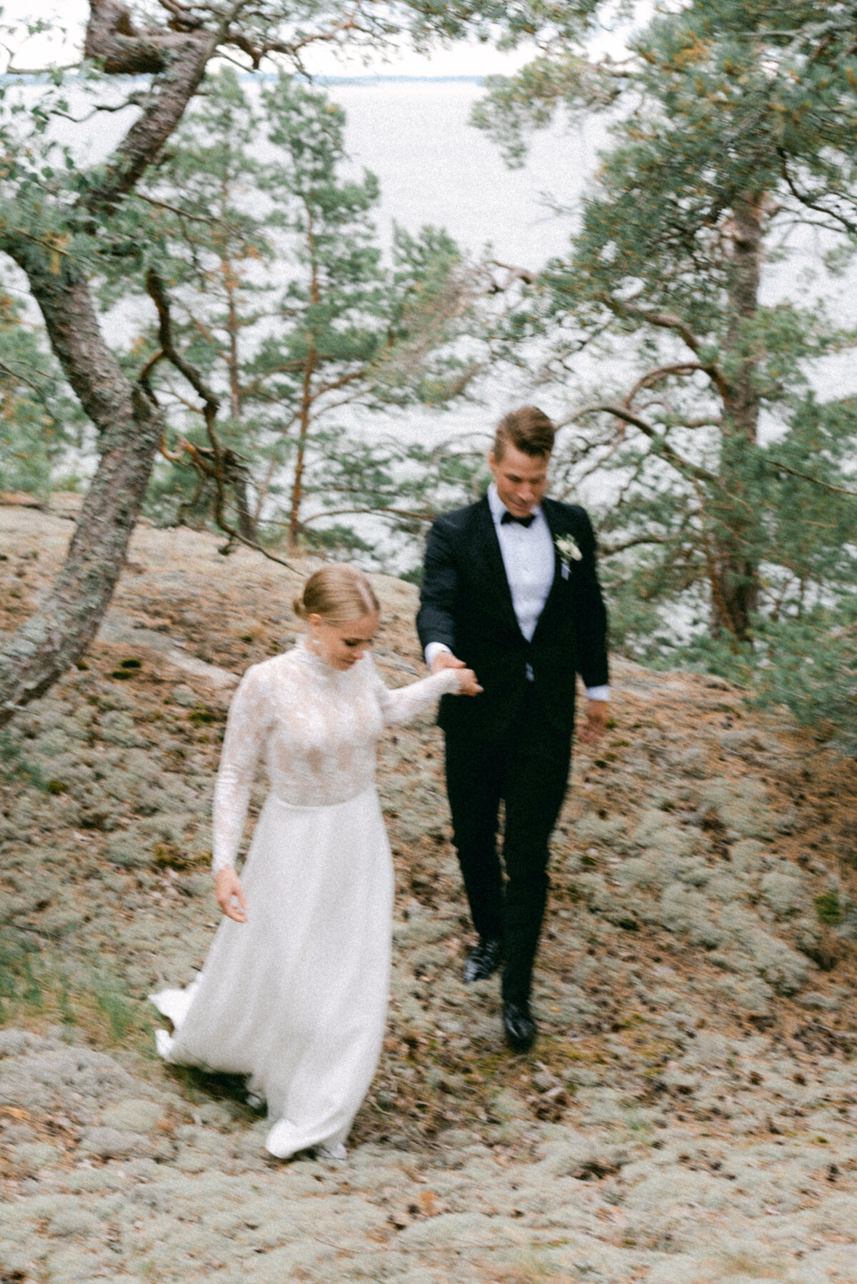 A wedding couple walking in the pine forest by the sea in Turku. A wedding photo captured by Finnish photographer Hannika Gabrielsson.