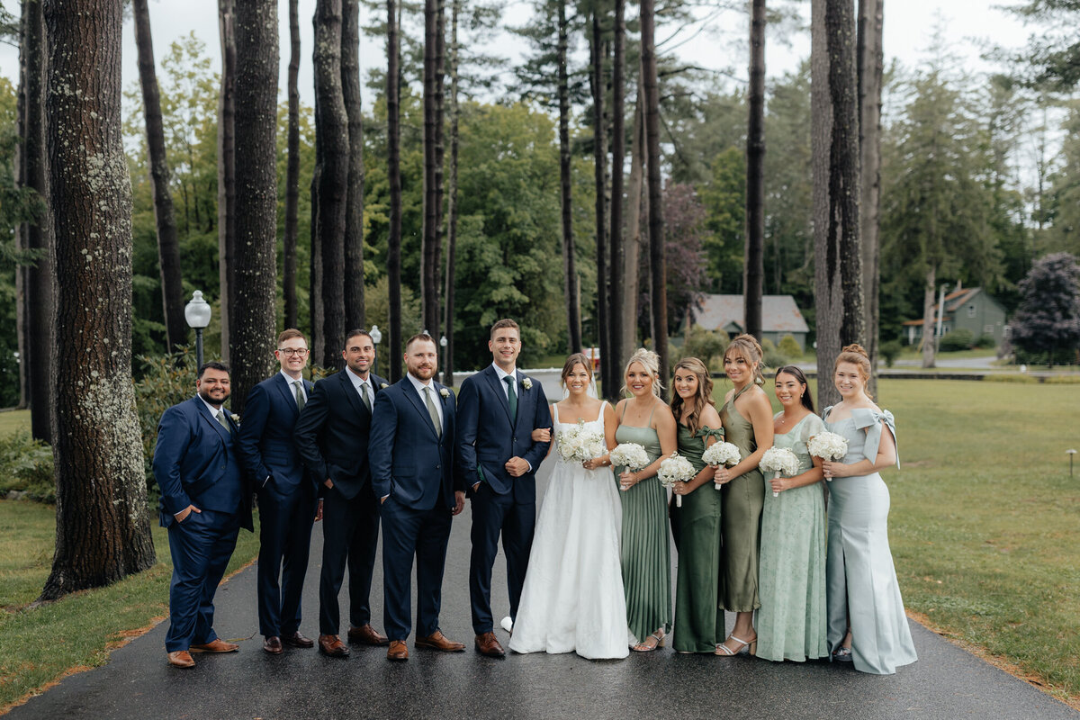 Wedding party walking together, smiling and relaxed, with Adirondack trees in the background