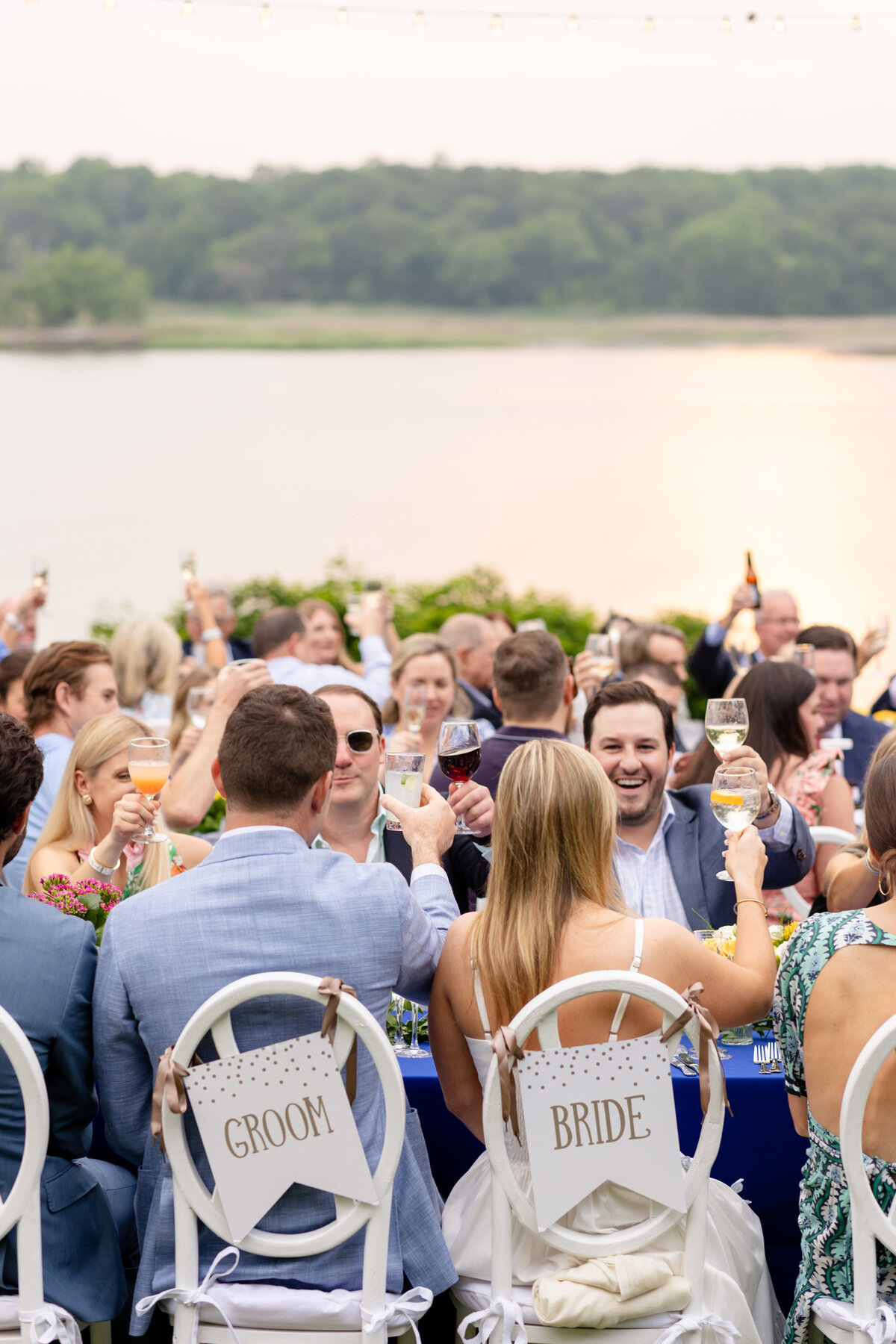 bride, groom, and guests laughing and toasting during rehearsal dinner speeches