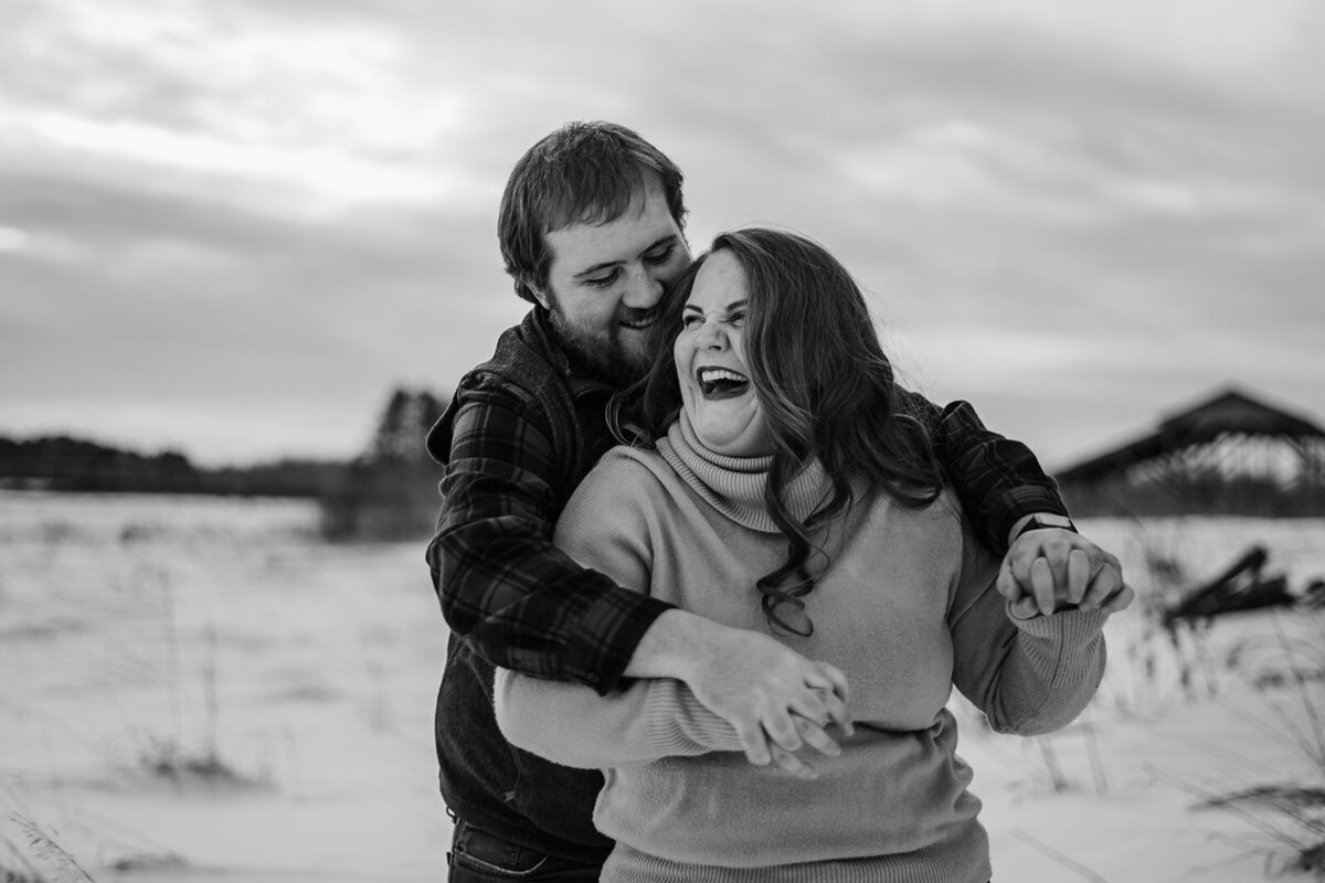 black and white photo of couple laughing in snow