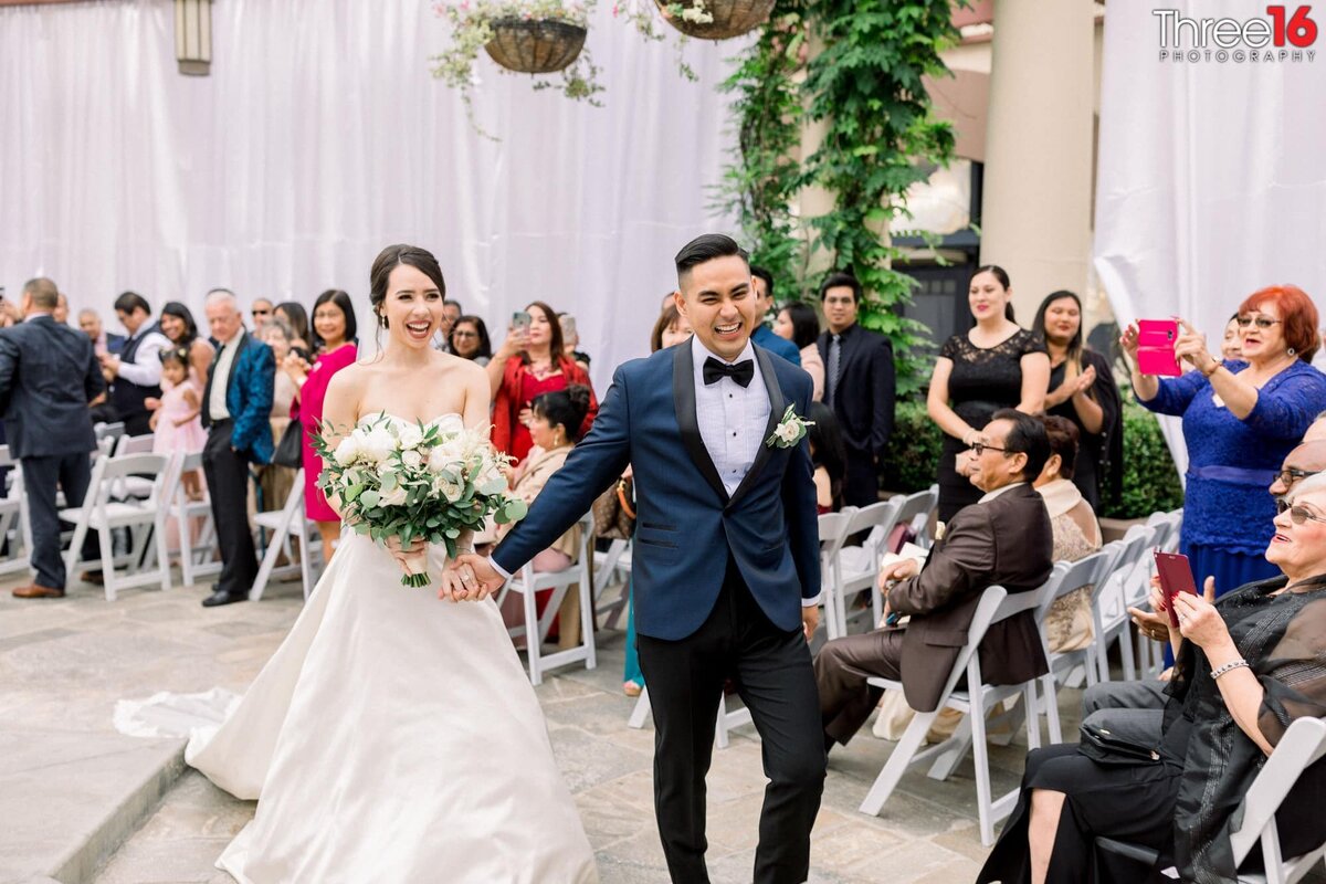 Groom leads Bride down the aisle after the ceremony as guests applaud
