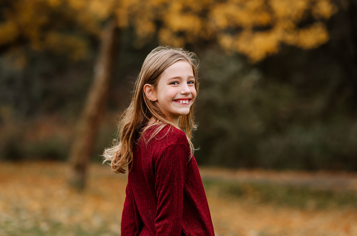 Adorable girl smiling brightly at the camera, capturing a genuine moment of happiness during a family photo session.
