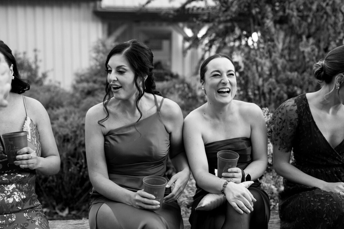 black and white wedding picture by Virginia wedding photographer with bridesmaids laughing and sitting together at cocktail hour