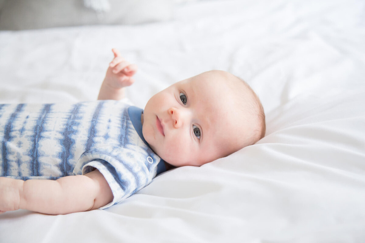 Baby boy on a white bed with an intent look on a white bed