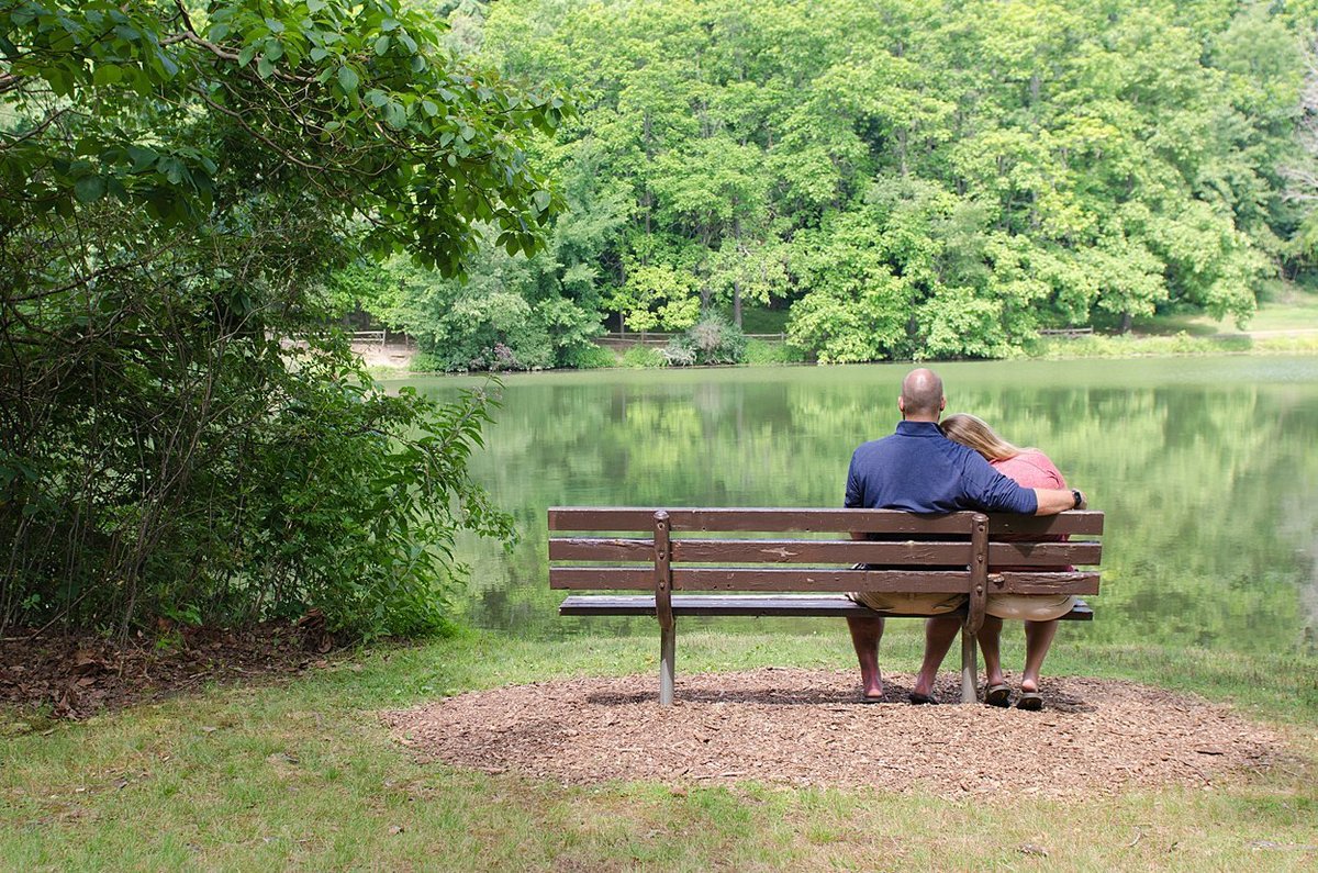 An engaged couple sits in silence on a bench overlooking a lake at Twin Lakes Park in Greensburg, PA