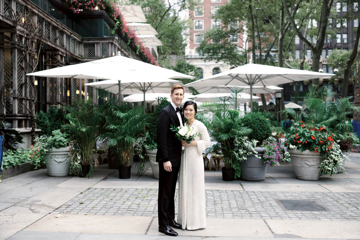 The bride and the groom are in front of a restaurant with lots of plants in the background. Image by Jenny Fu Studio