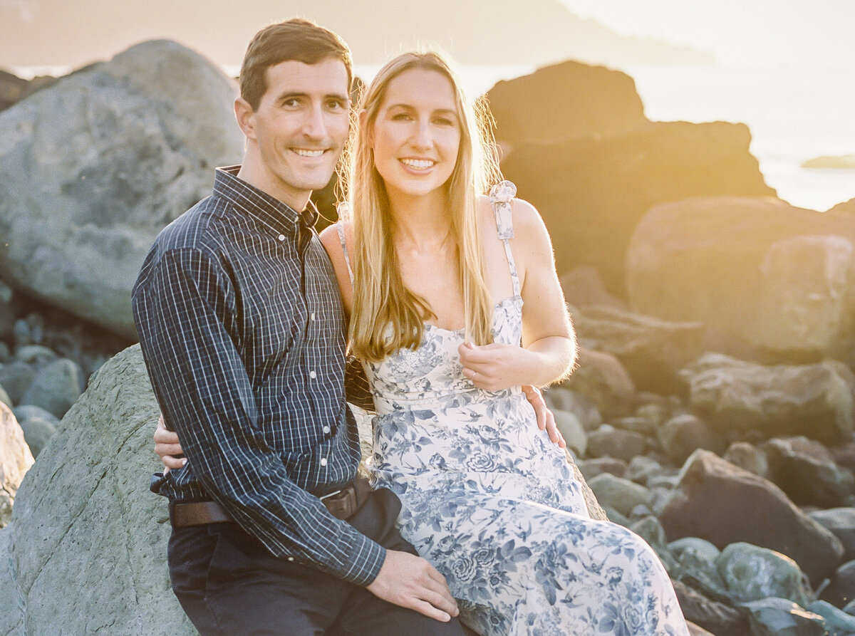 Wedding couple sitting on the rocks during sunset