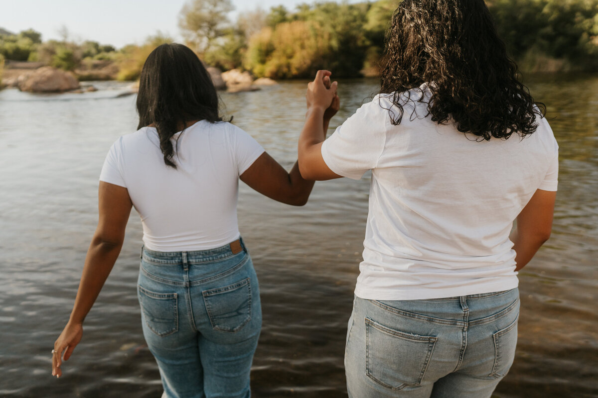 A couple holding hands and walking into a lake together  