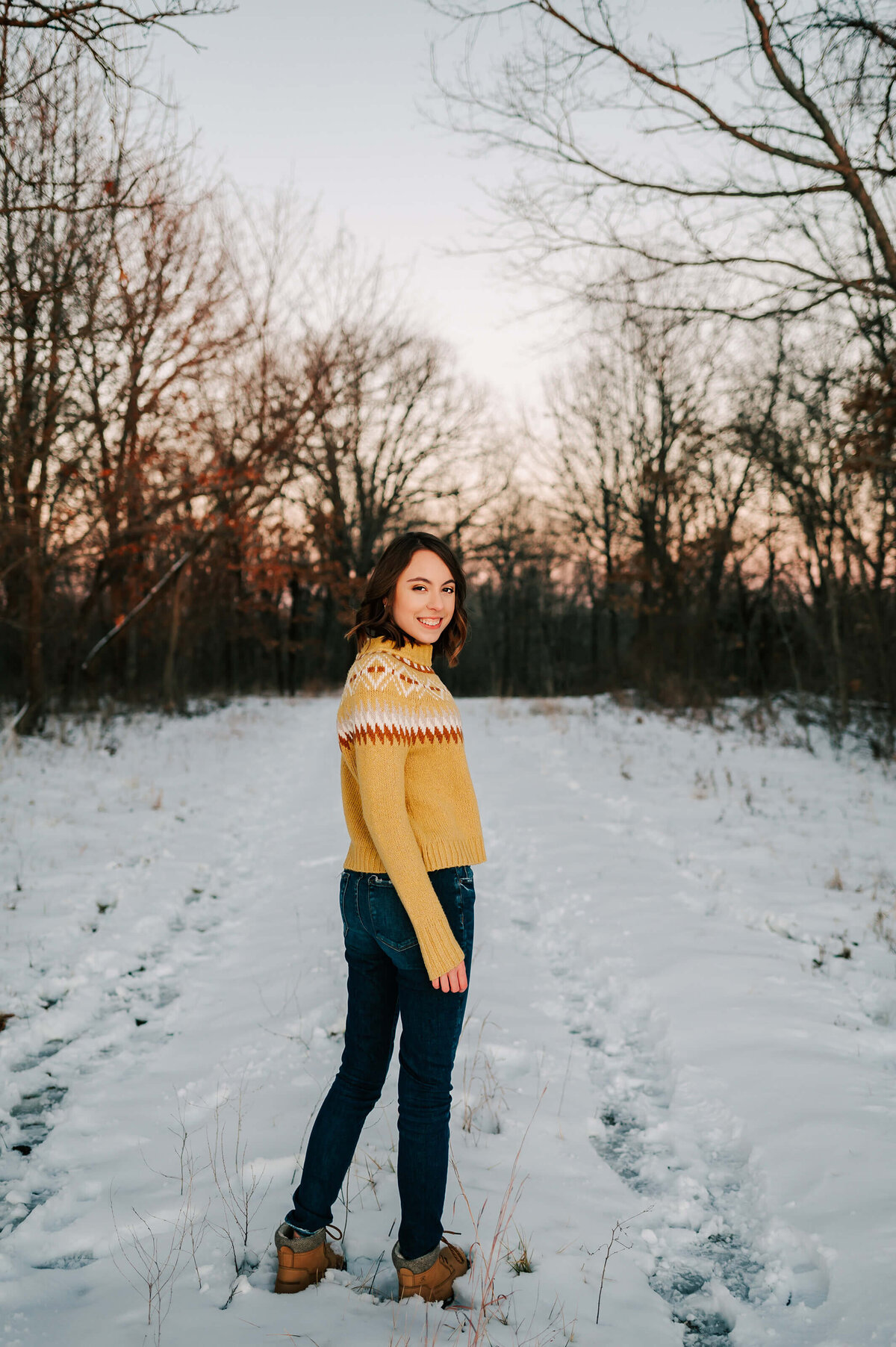 senior photo in Branson Missouri of girl smiling in snow in forest