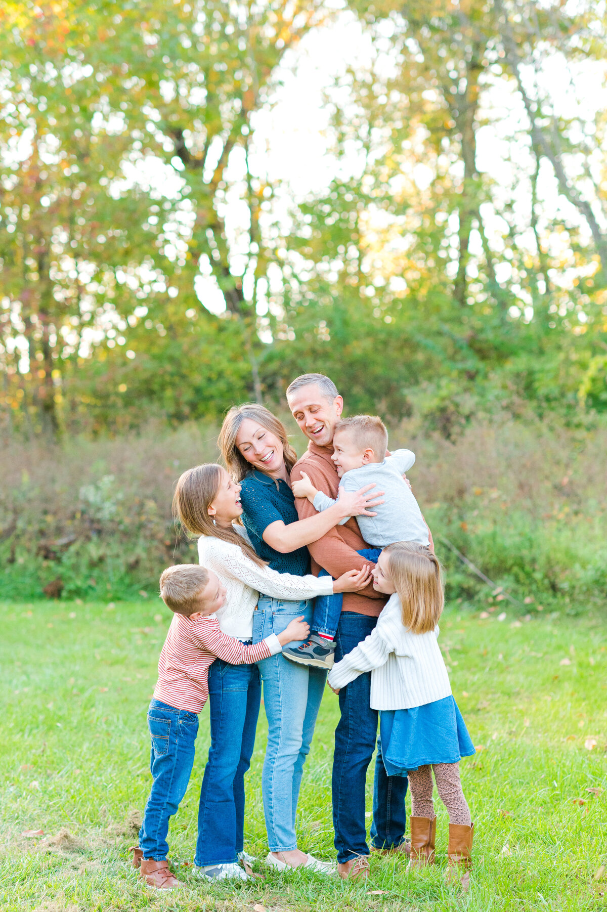 Family in Lancaster Pa park holding eachother and smiling as a family
